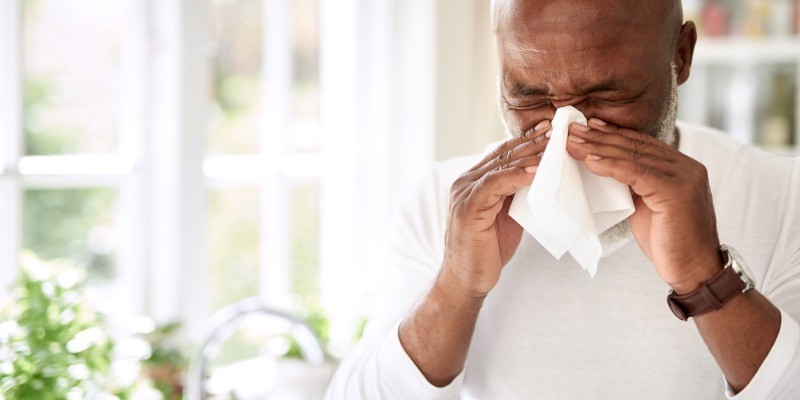 Man sneezing into tissue due to allergies