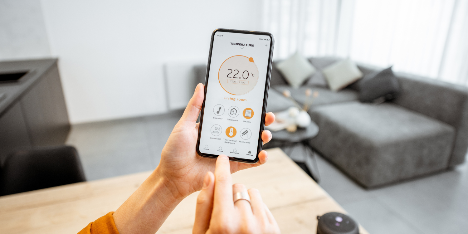 Lady adjusting thermostat on phone - Everything You Need to Know About Smart Thermostats