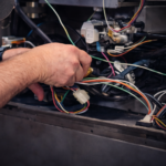 Commercial HVAC technician performing preventative maintenance inside rooftop unit